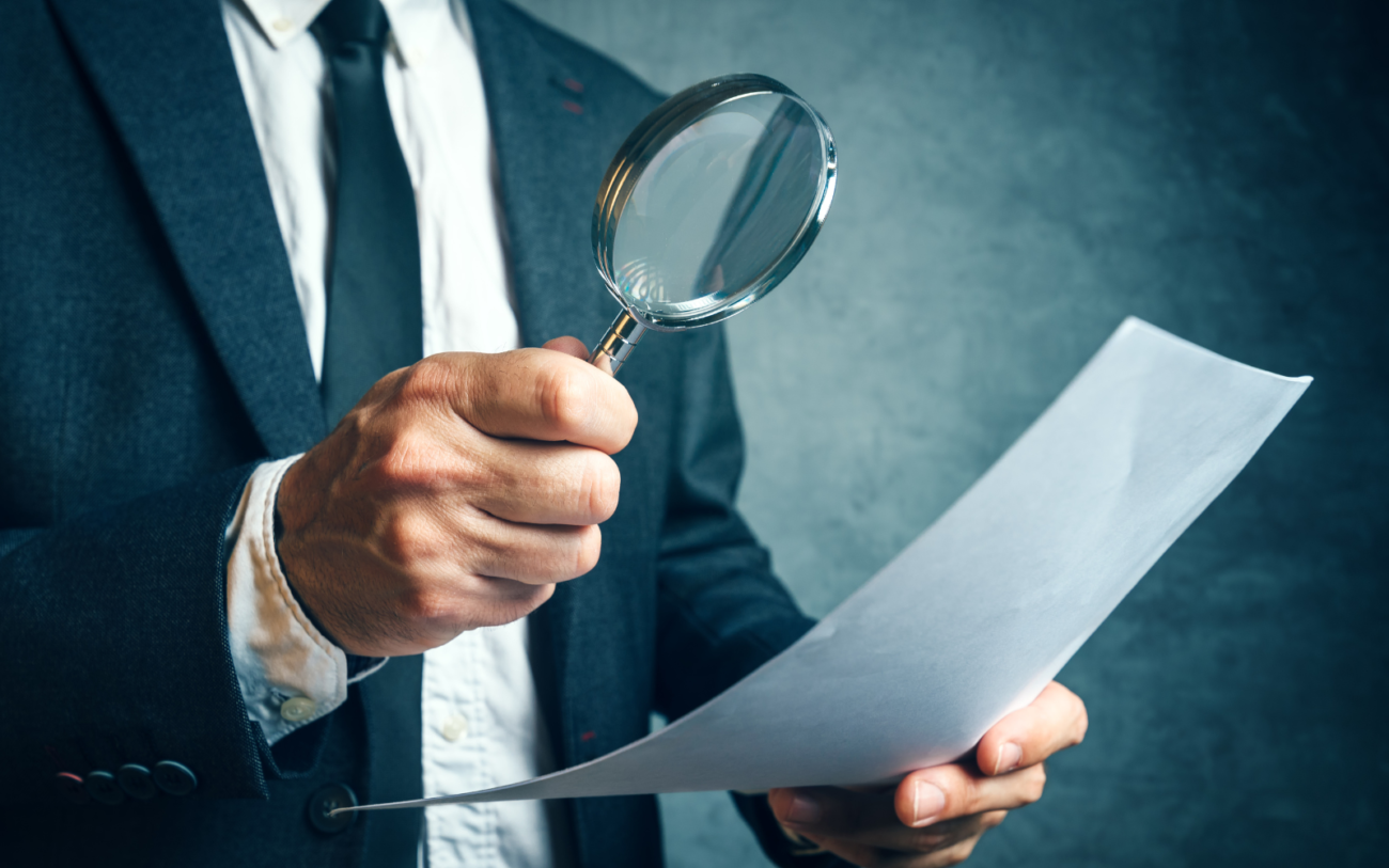 Man looking through a document with a magnifying glass