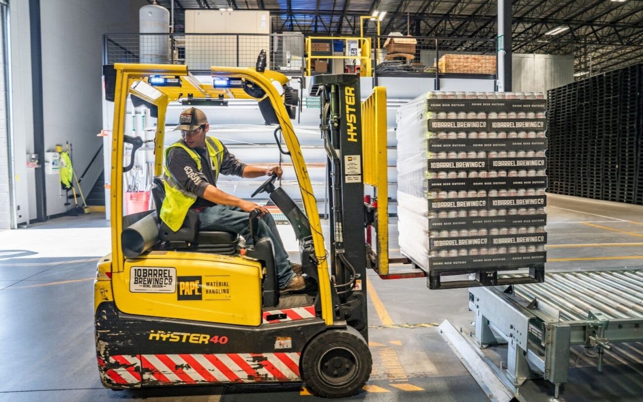 Male using a forklift truck to move stock in a factory